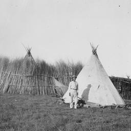 Man in a Yard with Two Tipi...